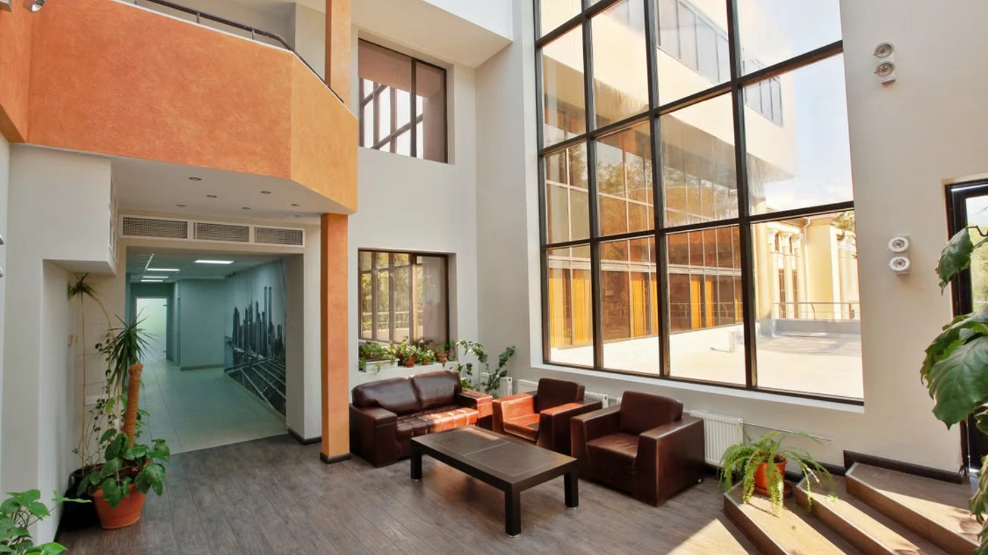 Intérieur lumineux d’un bâtiment moderne avec de grandes baies vitrées, illustrant un smart building confortable et économe en énergie.