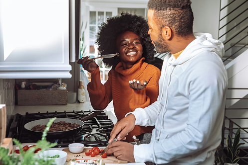 Couple préparant un repas dans une cuisine, illustrant la consommation d’énergie au quotidien dans un foyer.