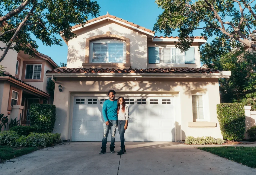 Couple devant une maison individuelle, illustrant un projet de rénovation d’ampleur résidentielle