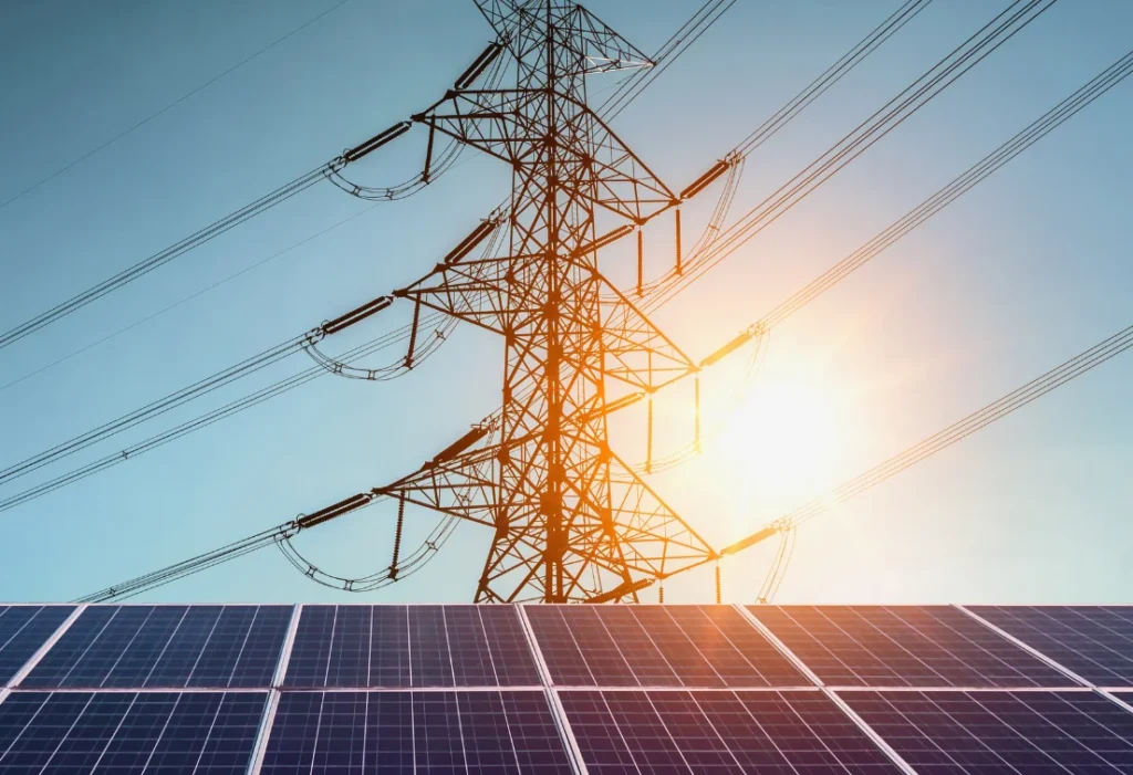 Panneaux solaires devant une ligne haute tension, illustrant la production et l’acheminement d’électricité renouvelable