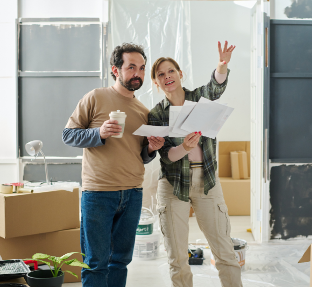 Couple consultant des plans dans un logement en travaux, illustrant un projet de rénovation d’ampleur