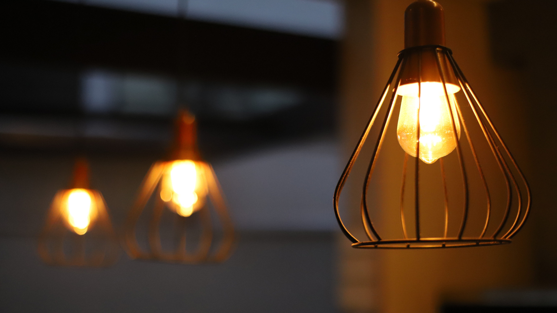 Suspensions design avec ampoules allumées dans un intérieur sombre illustrant la consommation d'électricité