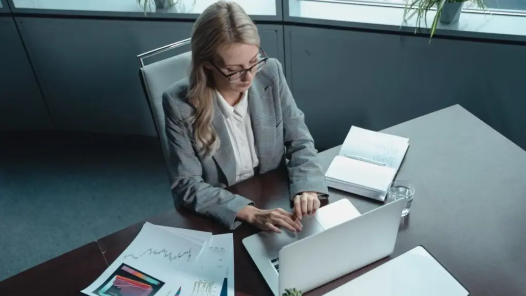 Professionnelle en tailleur consultant des graphiques financiers sur son ordinateur portable au bureau
