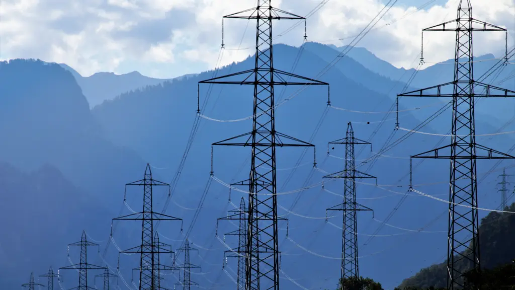 Lignes électriques haute tension et pylônes métalliques devant un paysage de montagne