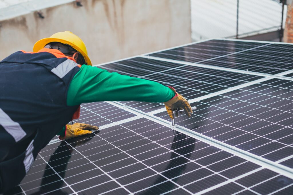 Technicien avec casque de chantier fixant des panneaux photovoltaïques sur une toiture
