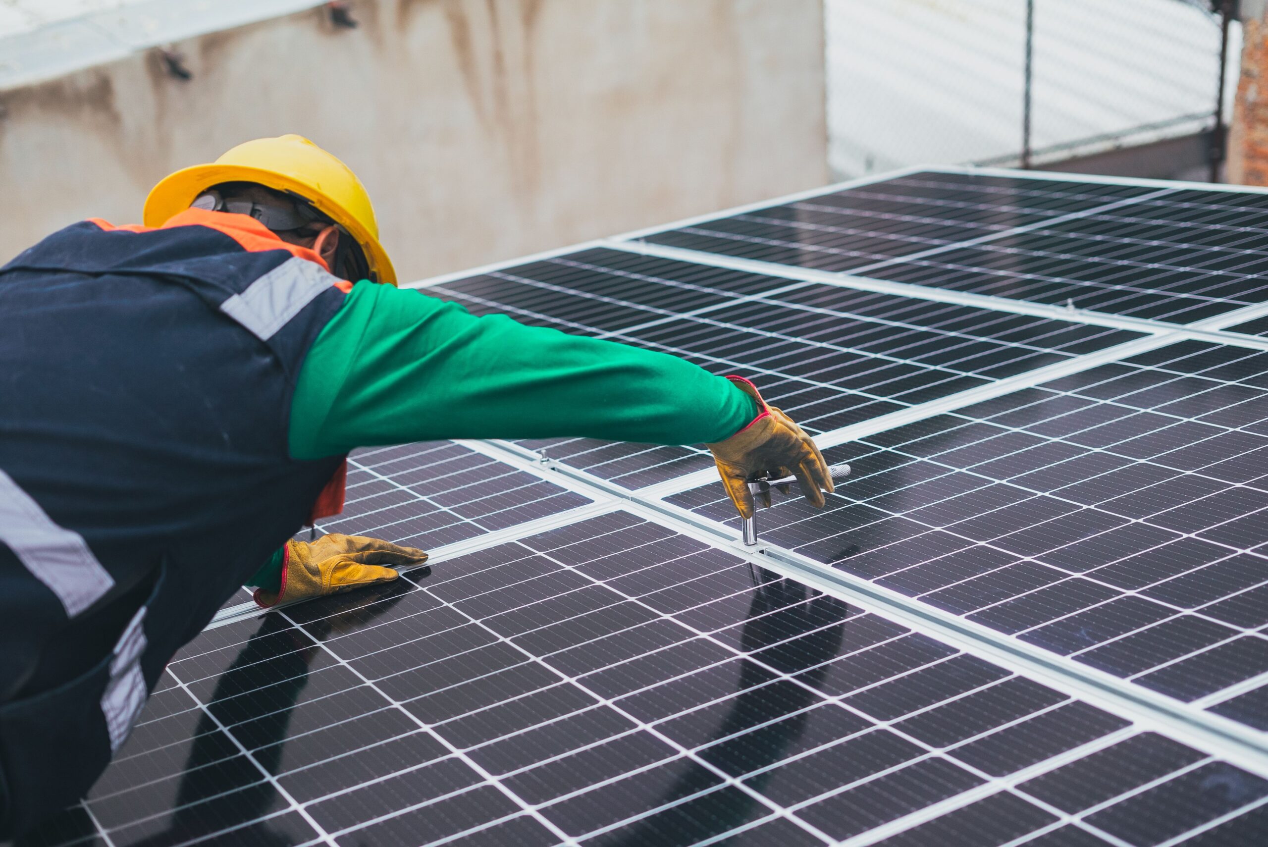 Technicien avec casque de chantier fixant des panneaux photovoltaïques sur une toiture